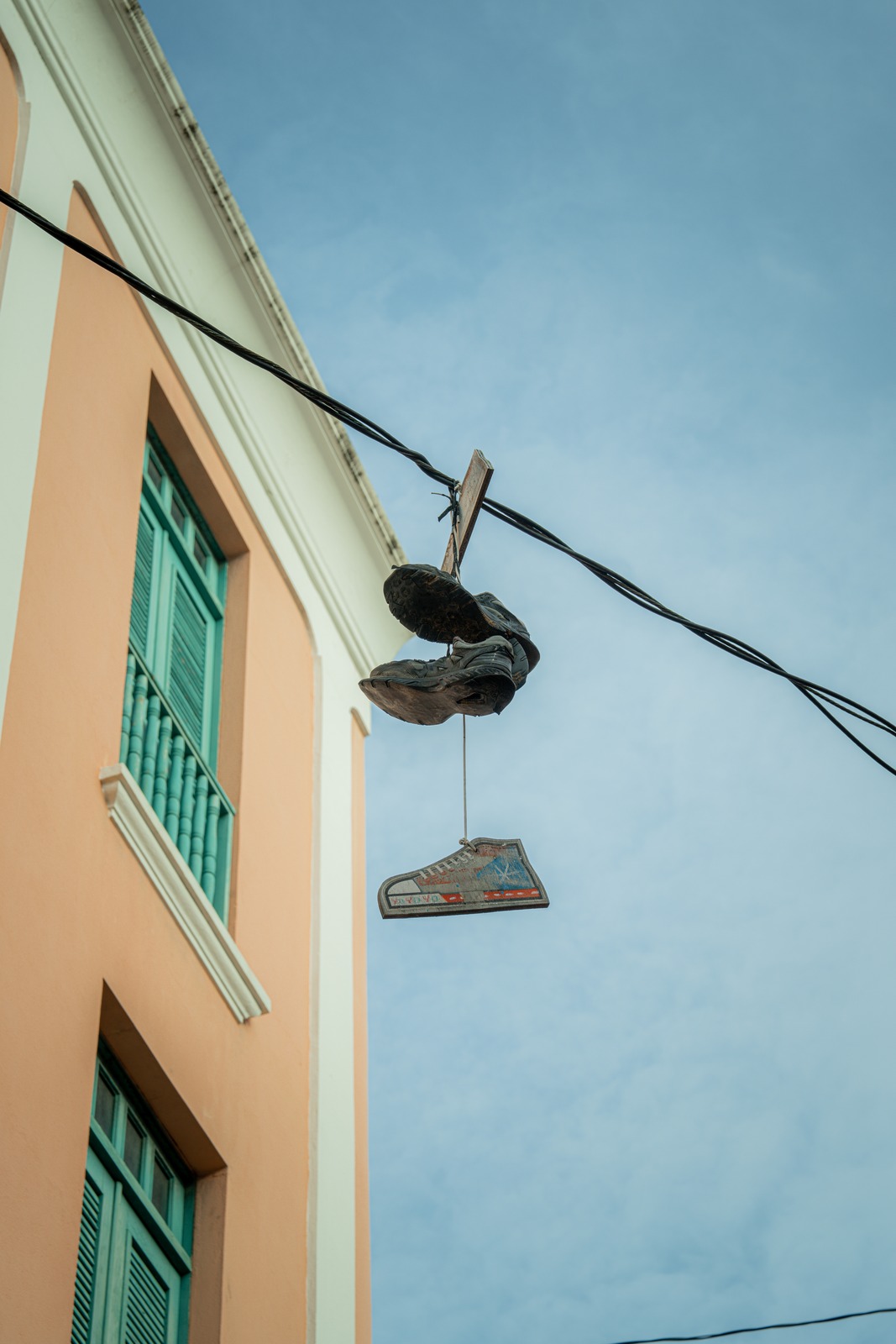 Shoes hanging from a wire beside pastel architecture and blue sky in Puerto Rico